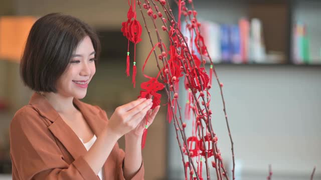 春节美丽的女人用柳条装饰房子，准备家庭团聚