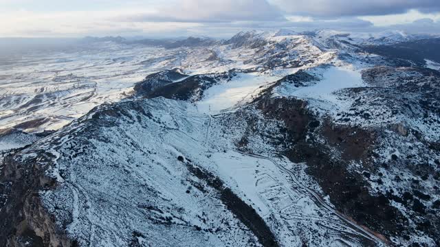 多云天空下雪山景观鸟瞰图。冬天的无人机视频。高质量4k镜头