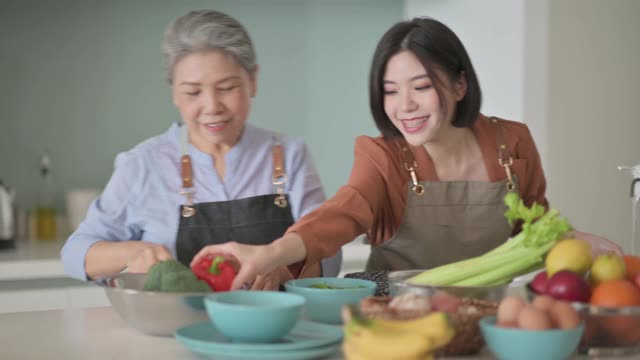 亚洲华人美丽的女人和她的母亲准备做饭为家人在厨房柜台