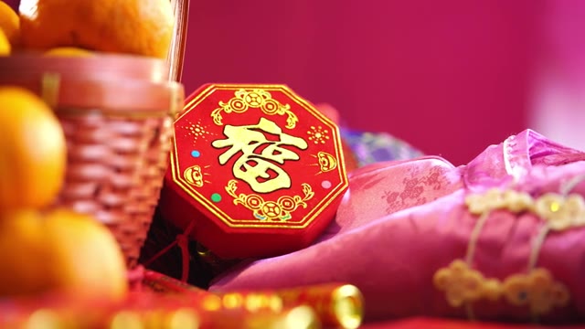 详情图-在粉红色的背景下，木桌上放着一篮橘子、中国红包和其他春节装饰品