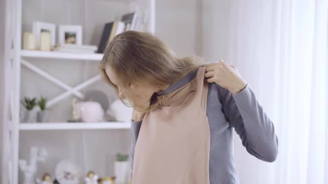 中景肖像幸福美丽的年轻女子在家里欣赏新衣服。快乐的白人女士试衣服和微笑。幸福和时尚的概念。