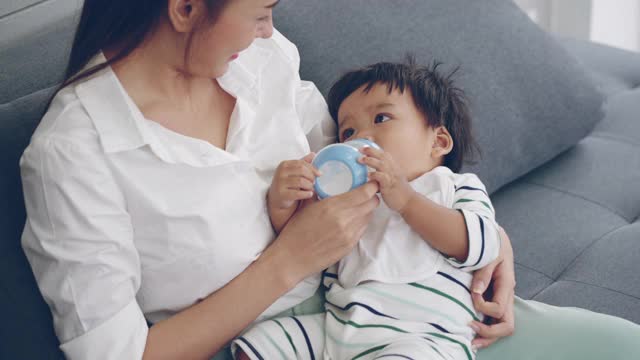 亚洲父母在家客厅给男婴喂奶