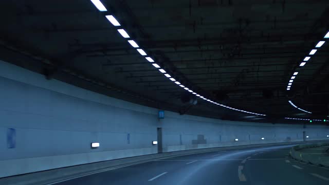 一辆车在夜间行驶在高速公路的隧道里