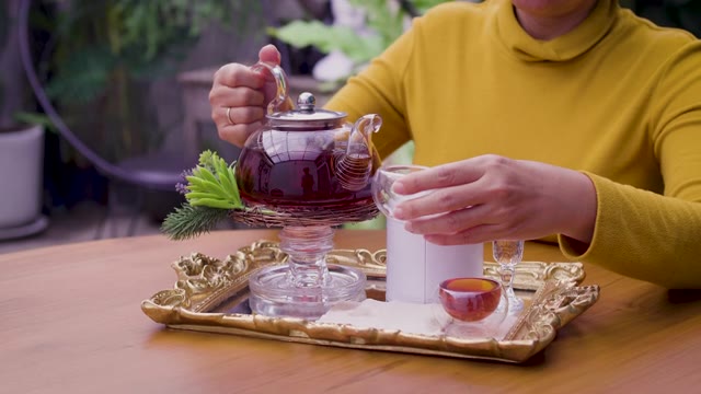详情图-女子将茶从玻璃壶倒入杯中，茶道概念