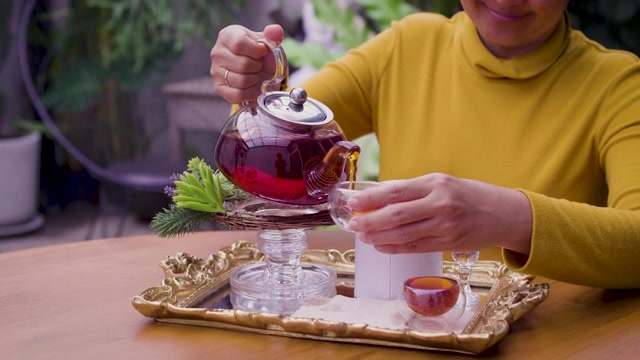 详情图-女子将茶从玻璃壶倒入杯中，茶道概念