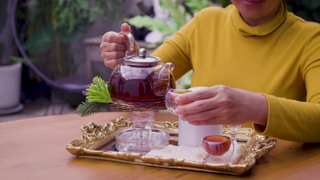 详情图-女子将茶从玻璃壶倒入杯中，茶道概念