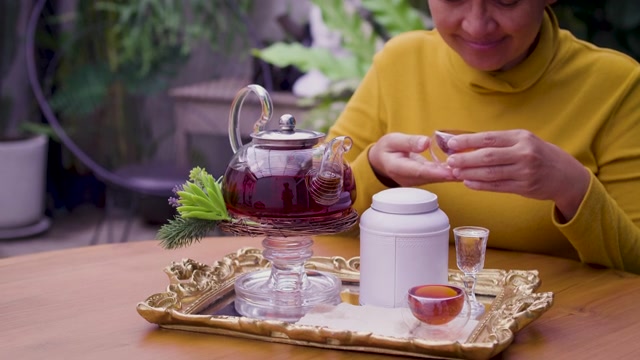 详情图-女子将茶从玻璃壶倒入杯中，茶道概念