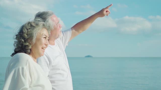 亚洲老年夫妇在海滩上的快乐时光，慢镜头。