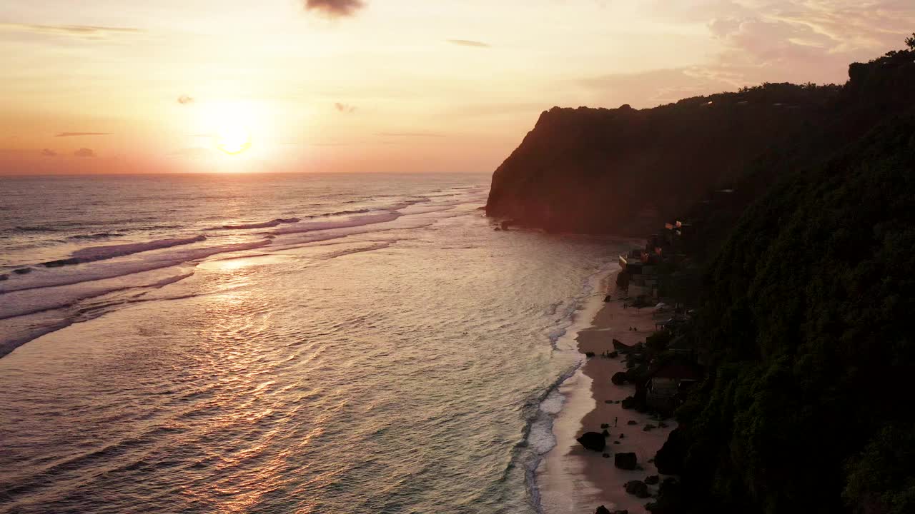 夕阳下的白色沙滩沿悬崖在巴厘岛