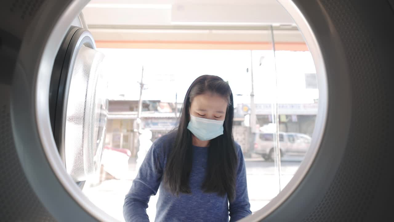 女人把衣服放进洗衣机