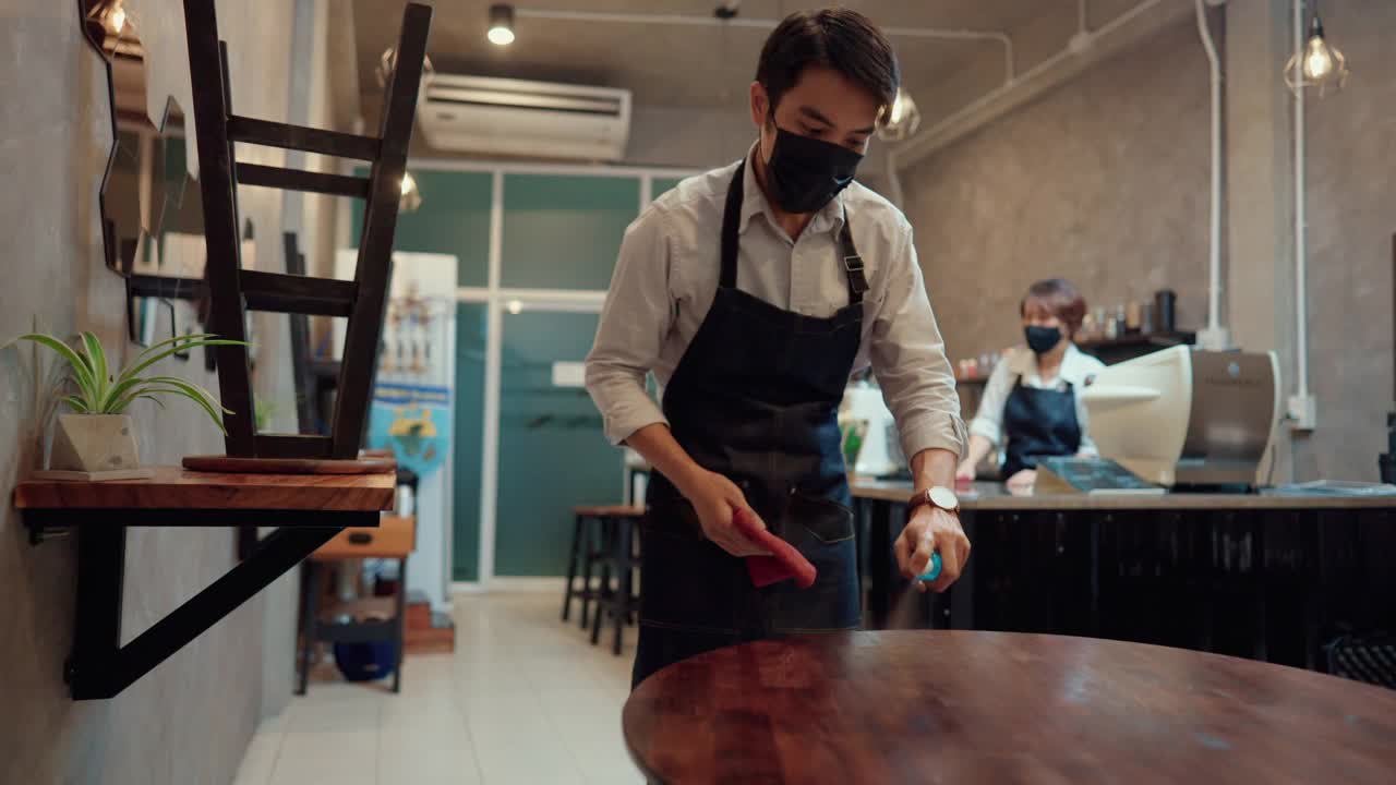 一对夫妇的老板戴着外科口罩在一个封闭的咖啡馆里。