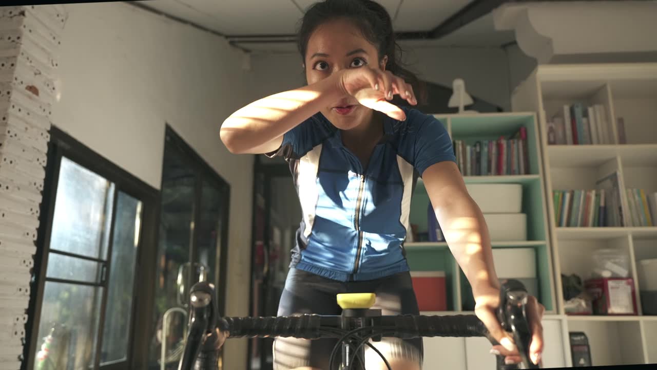 详情图-亚洲女人骑自行车。她在家锻炼。她在虚拟世界里玩游戏。