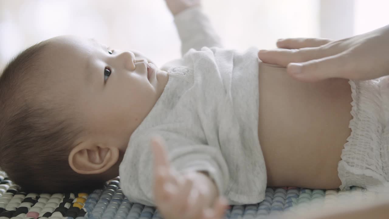 妈妈在给她3个月大的儿子换衣服