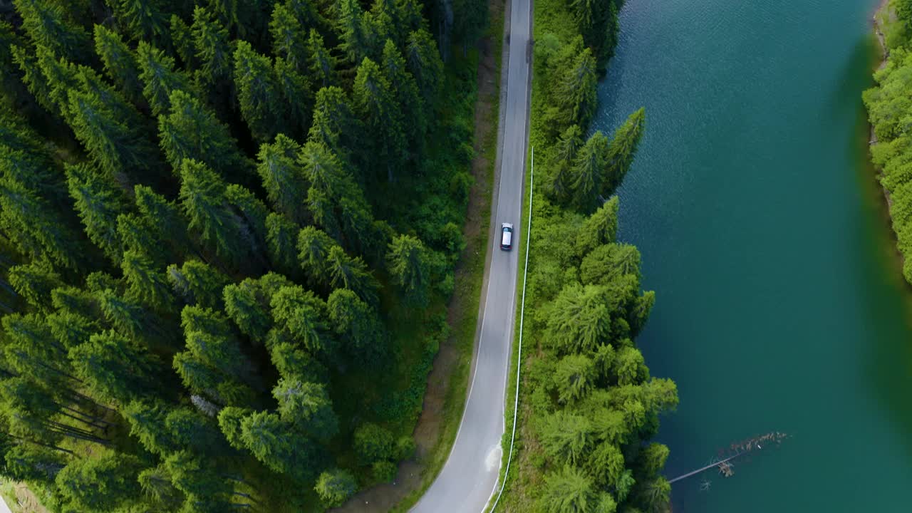 鳥瞰圖的汽車駕駛通過森林和湖的一邊。美麗的山路。在山路上開車。公路旅行。山地森林湖泊景觀。汽車駛過松林