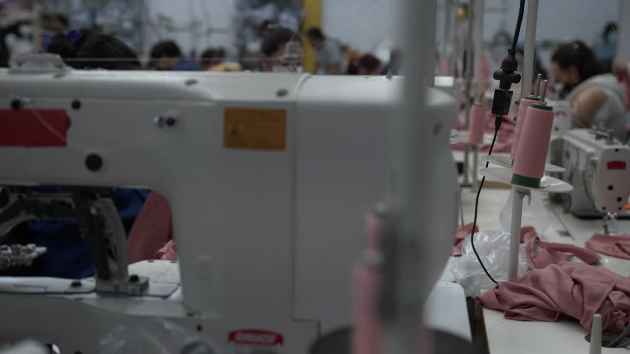 拉丁美洲的女蓝领工人在服装厂各自的工作站工作