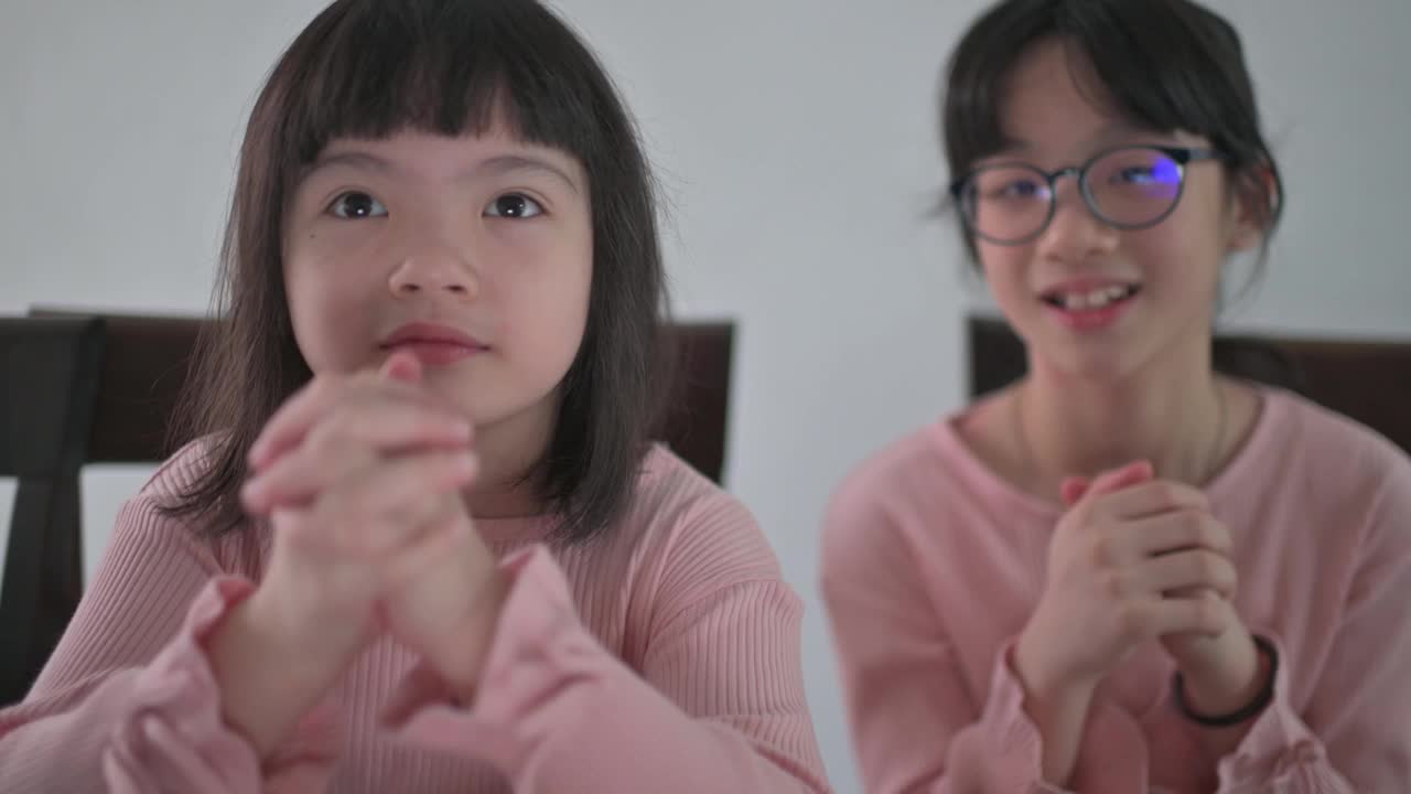 亚洲的中国小女孩和她的妹妹看着笔记本电脑的摄像头，用红包和橘子向她的祖父母祝贺春节