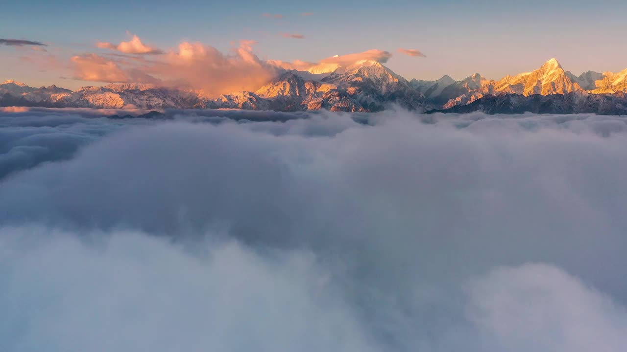 日出时，云海在雪山前翻滚，显得格外壮观