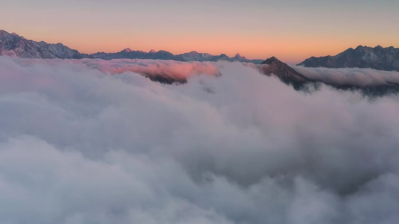 日出时，云海在雪山前翻滚，显得格外壮观