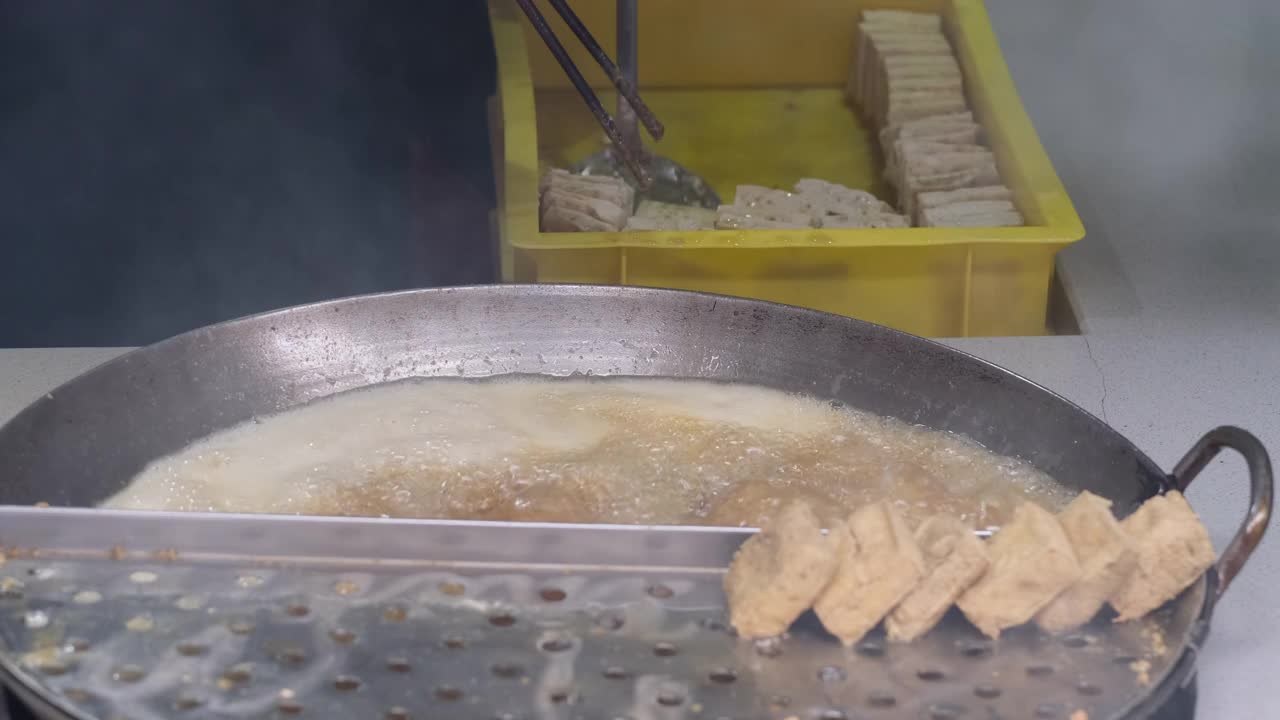 近距离拍摄人们油炸臭豆腐的画面。中国传统小吃