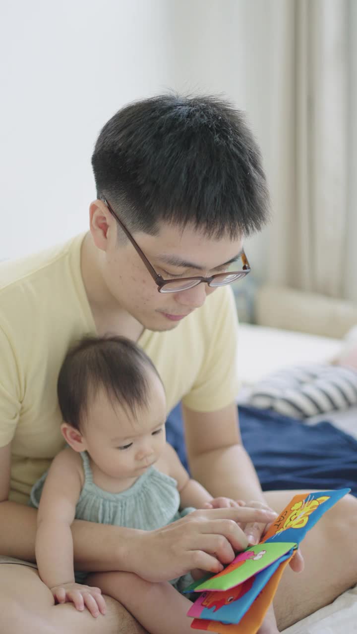 垂直亚洲年轻的父亲阅读儿童书籍与他的女儿
