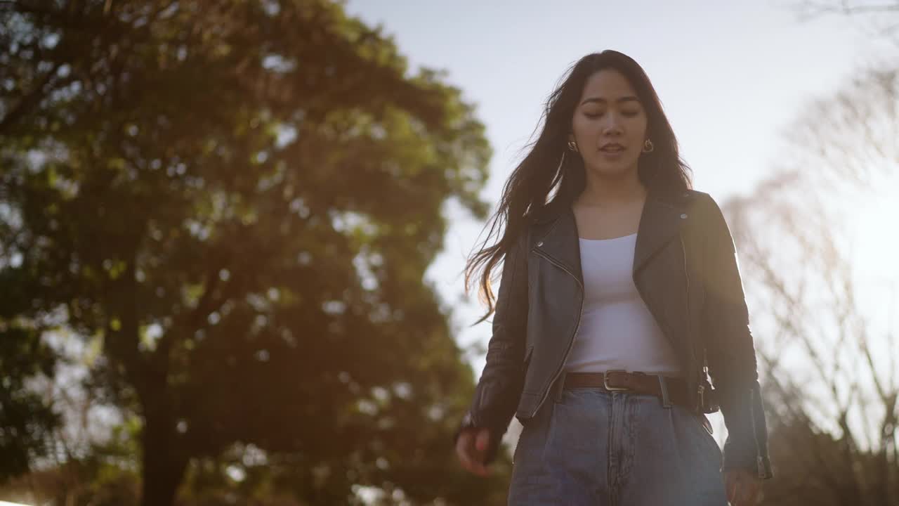年轻女子愉快地在公园里散步，听着音乐