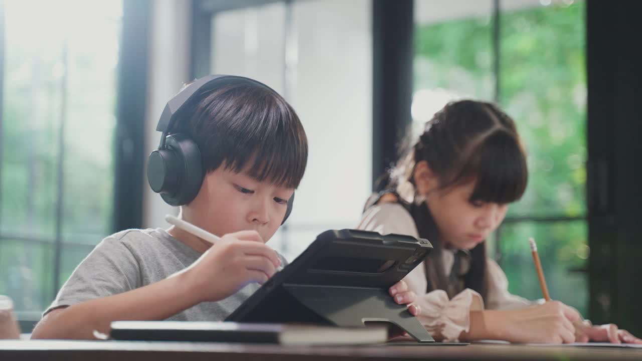 由于冠状病毒大流行，亚洲小女孩通过数字远程互联网会议从学校老师那里学习在线课程。孩子看着电脑笔记本电脑屏幕，那个女人在教书。