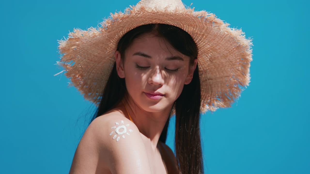 一名年輕女子把防曬霜涂在肩膀上，對著鏡頭微笑
