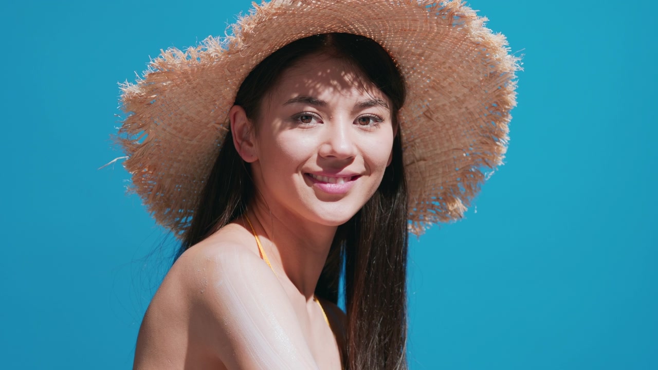 詳情圖-一名年輕女子把防曬霜涂在肩膀上，對著鏡頭微笑