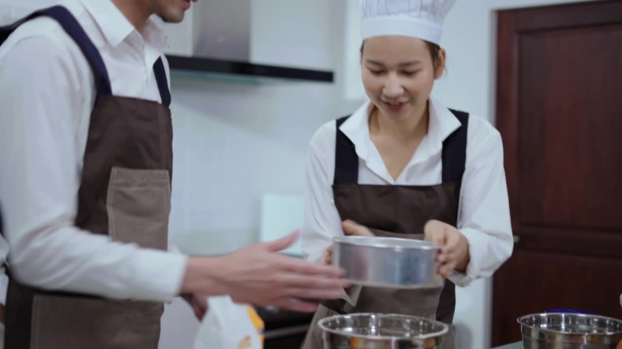 一对年轻夫妇筛面粉做面团做面包房