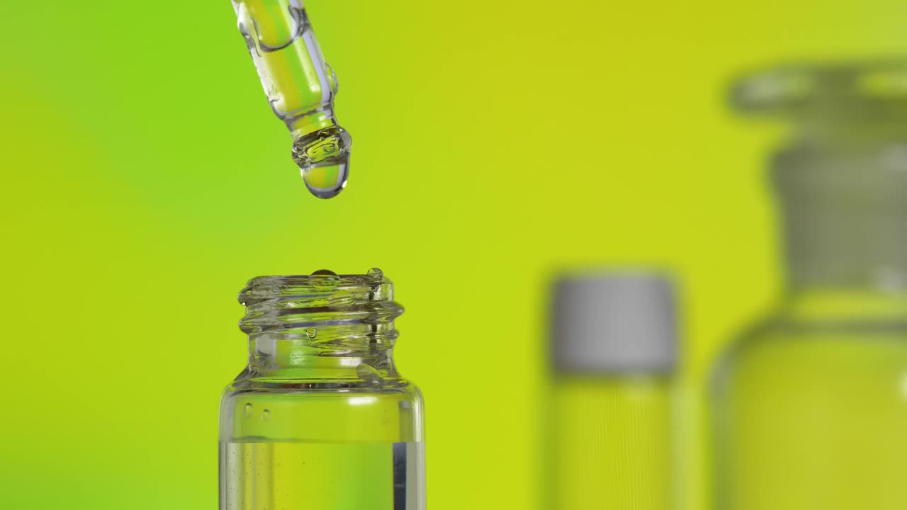 透明的油滴从玻璃瓶中的吸管中落下