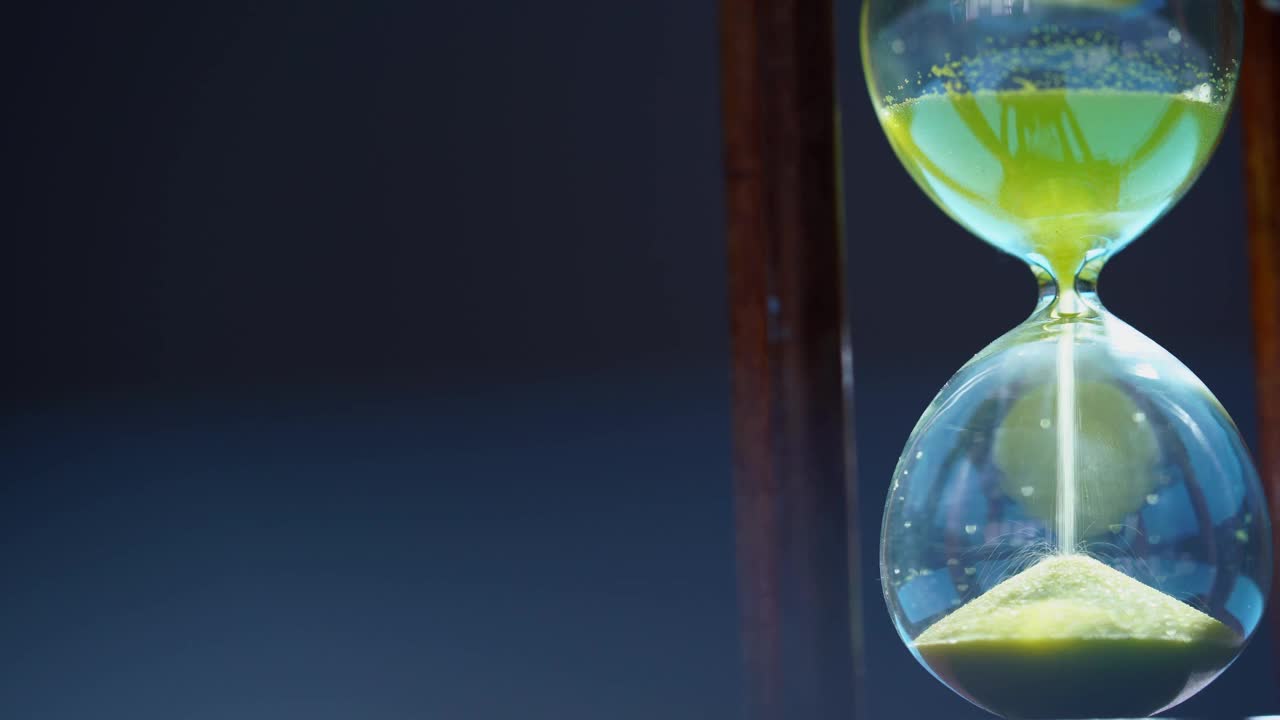 模糊的黑色背景上的沙漏。时间就是金钱。