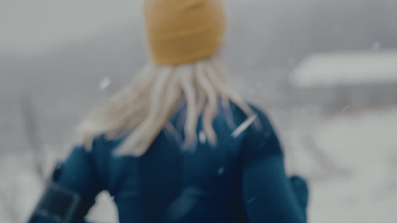 女人在雪地里慢跑时看她的智能手表