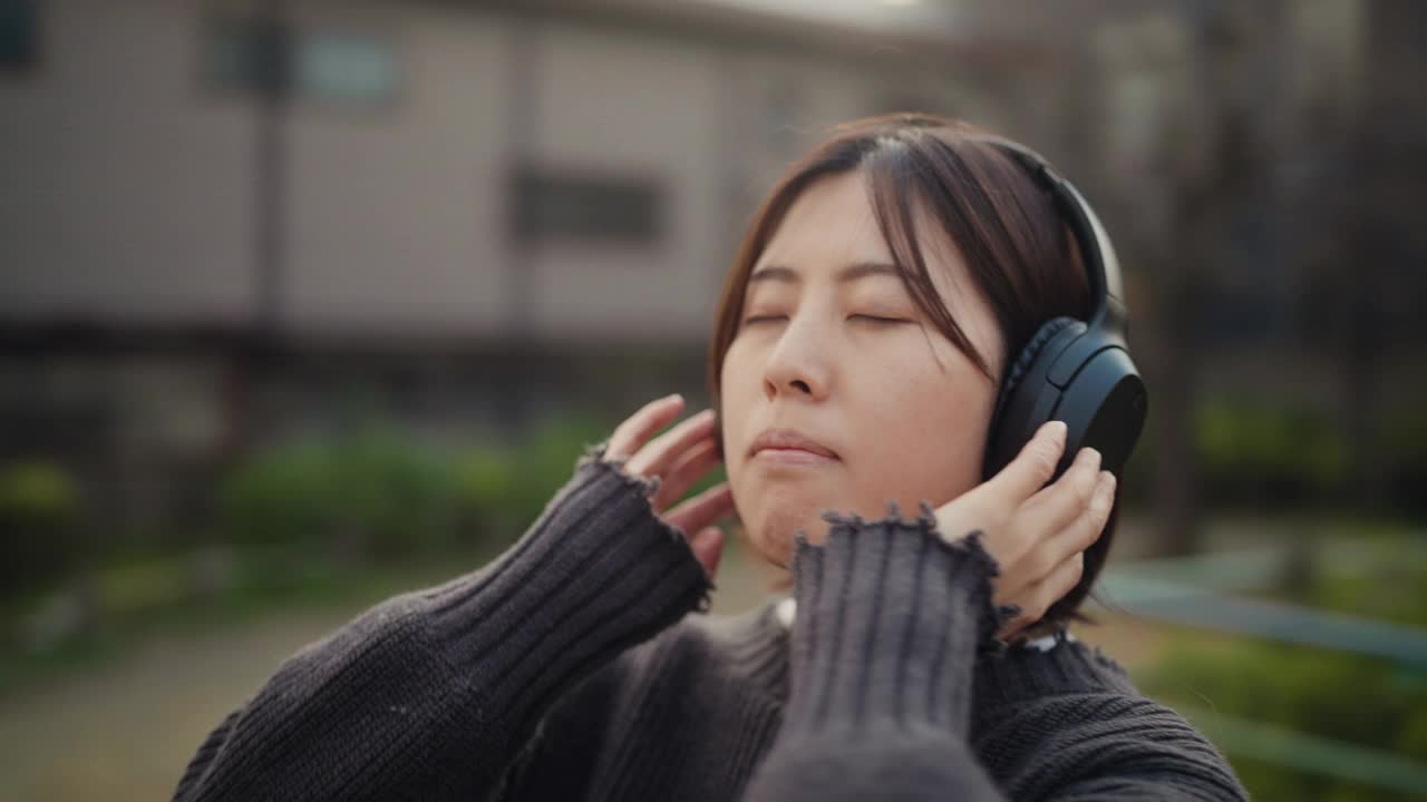 360度旋转视频肖像年轻女子听音乐在公园