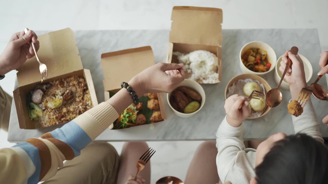 俯视图亚洲华人年轻家庭在客厅的电视前享受周末的食物
