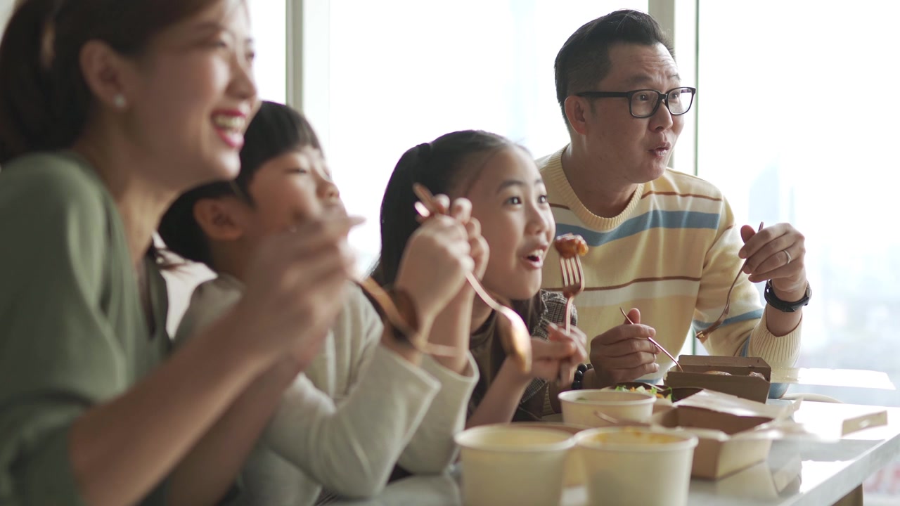 詳情圖-亞洲華人年輕家庭周末在客廳的電視前享受外賣食物