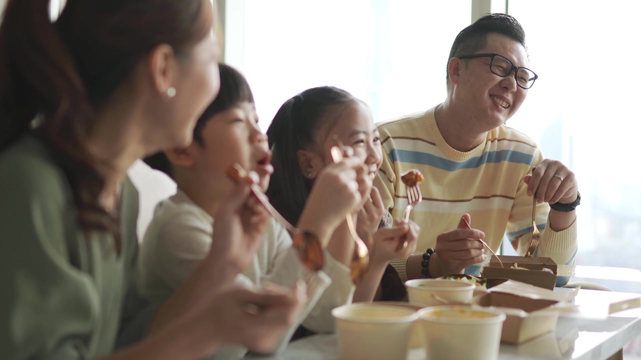 詳情圖-亞洲華人年輕家庭周末在客廳的電視前享受外賣食物