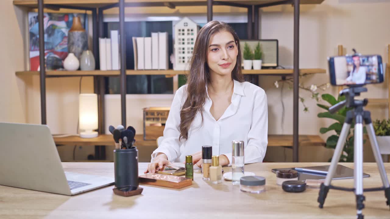 亚洲年轻女性博主录制视频与化妆化妆在家在线影响社交媒体概念。直播病毒