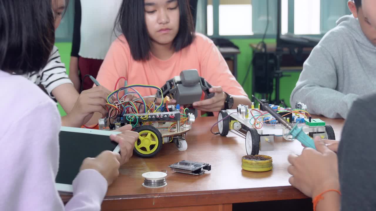 中学阶段:教师向孩子们讲解如何使用机器人程序，让孩子们饶有兴趣地学习。