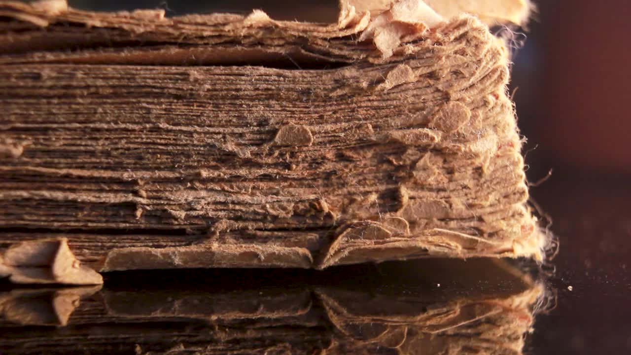 时间和知识的概念，一副眼镜，放在一本破旧的，部分损坏的宗教经书前。极端微距特写镜头的一个旧的损坏和老化的古董书