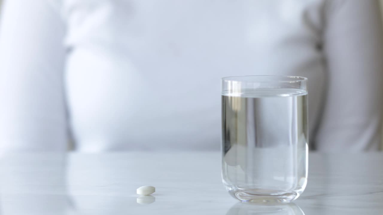 一个女人在吃一粒药和一杯水