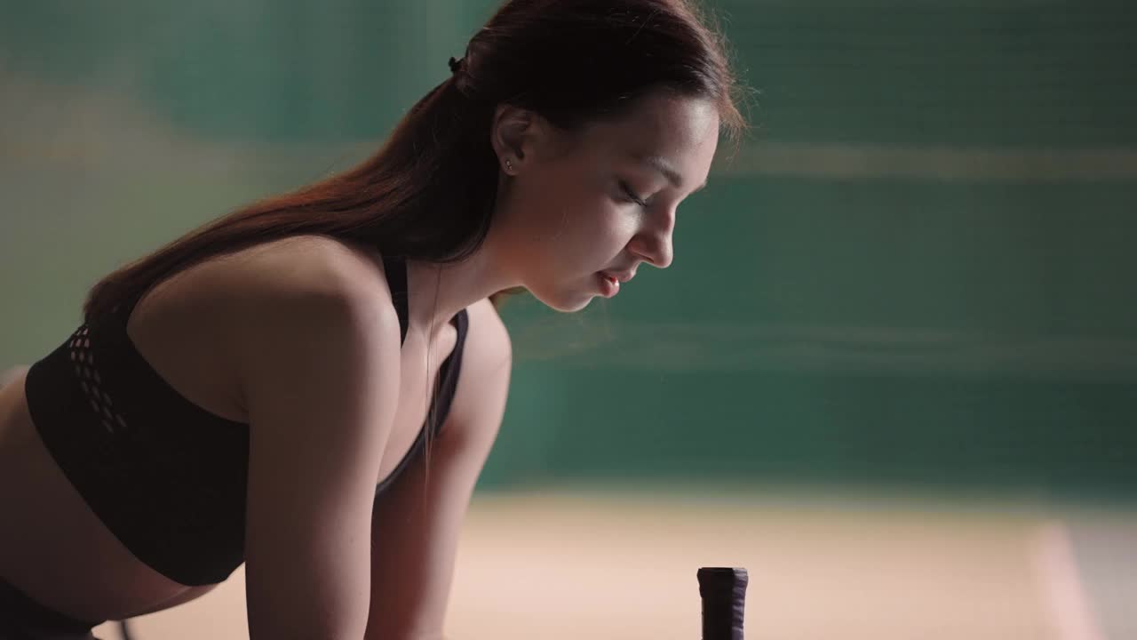 年轻女子网球运动员的肖像，女运动员正坐在网球场的长椅上，中拍