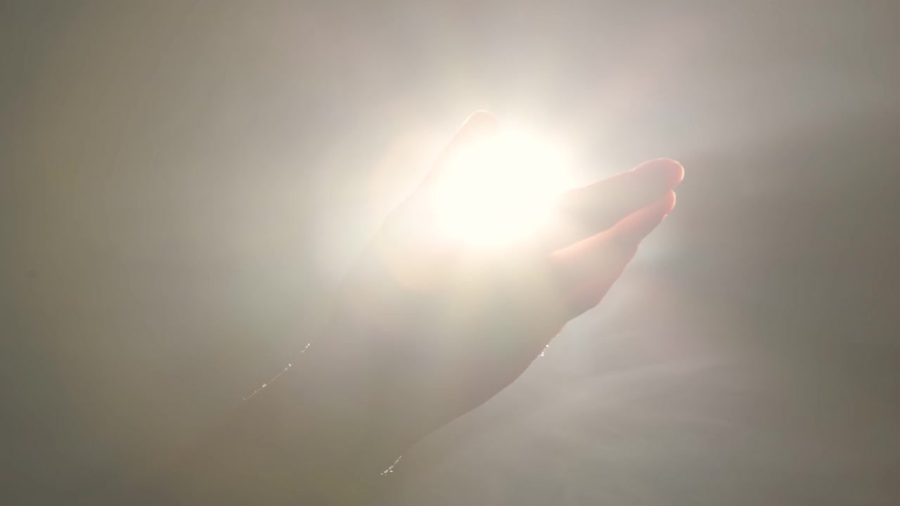 詳情圖-女性的手輕輕地觸摸著太陽(yáng)或聚光燈。深色背景，輕煙。光輝、溫暖、啟迪的觀念