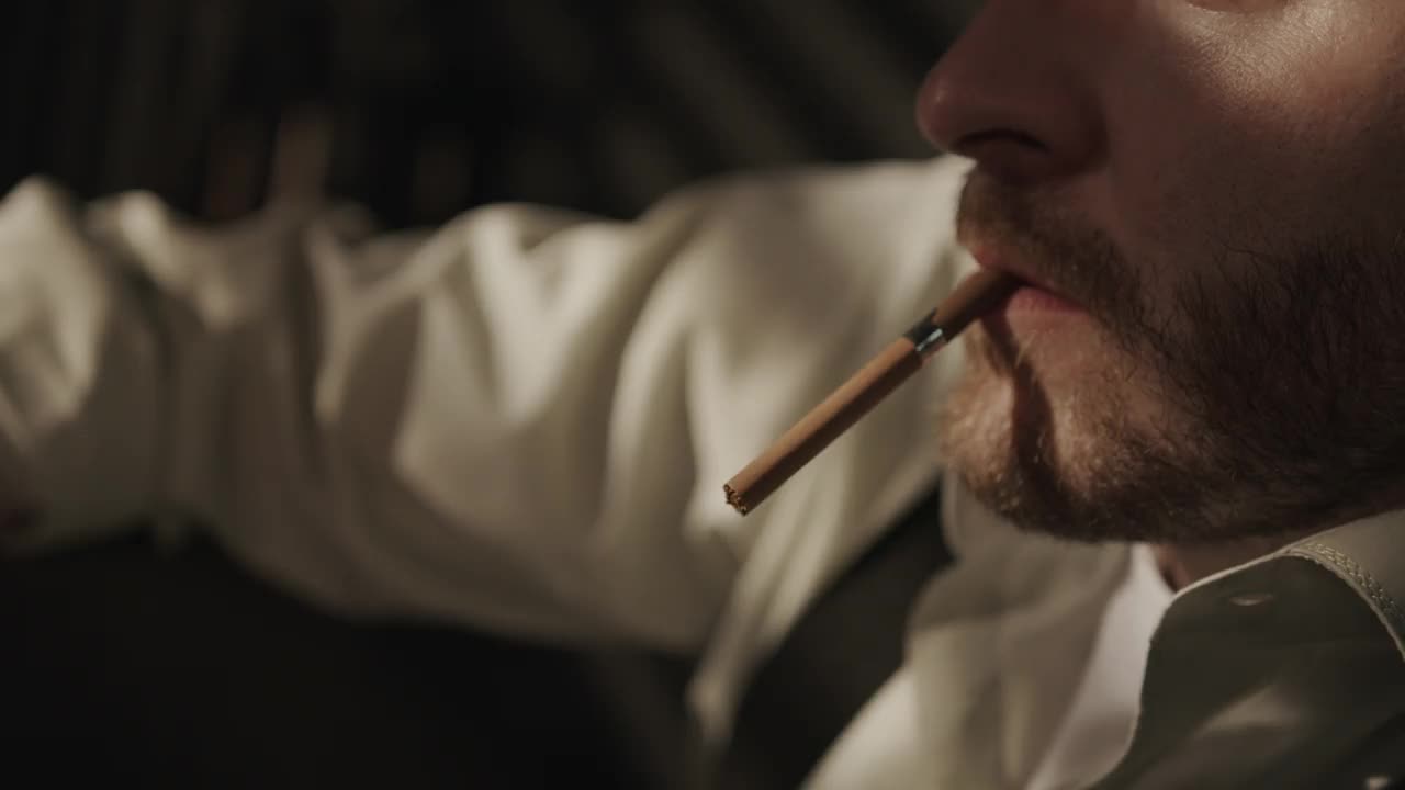 一个醉汉的特写镜头，在黑暗中点燃一支香烟，抽了起来