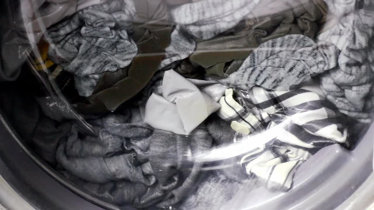 近距离观察快速旋转洗衣机滚筒旋转脏衣服与水在家中洗衣