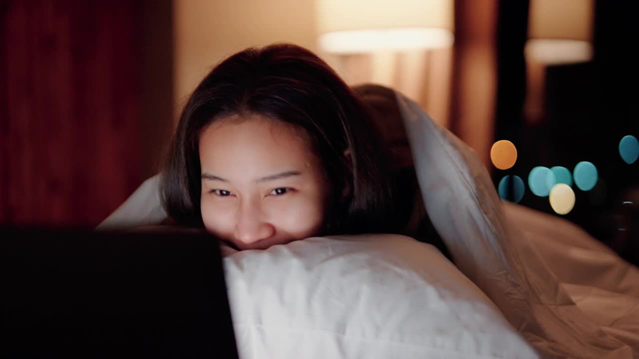 睡眼惺忪的女人在床上看电影。