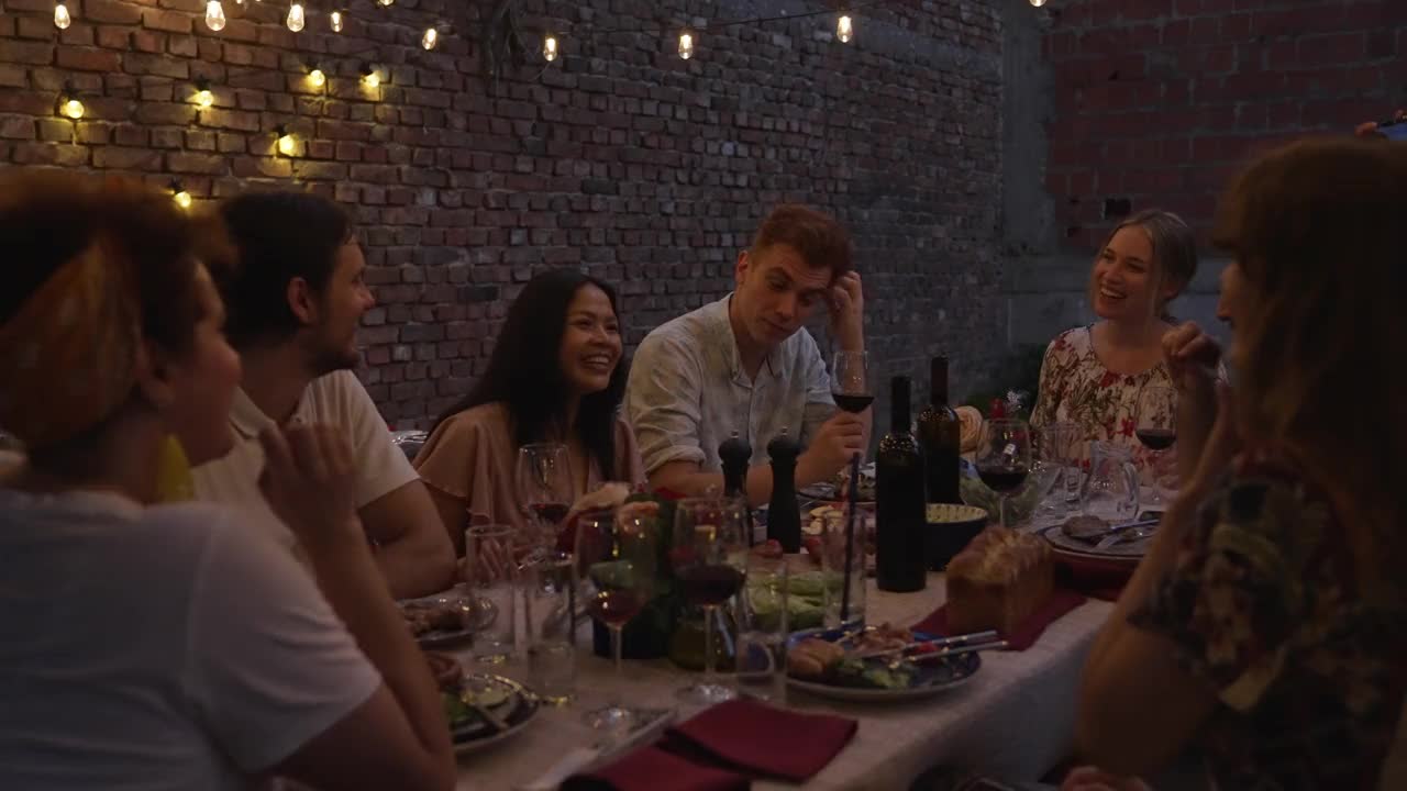 夏日夜晚，朋友们在后院的晚宴上互相敬酒