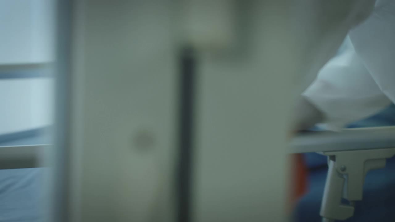 专科医生男穿着防护服和口罩在医院病房病房内进行表面消毒，4K分辨率，COVID-19效果，