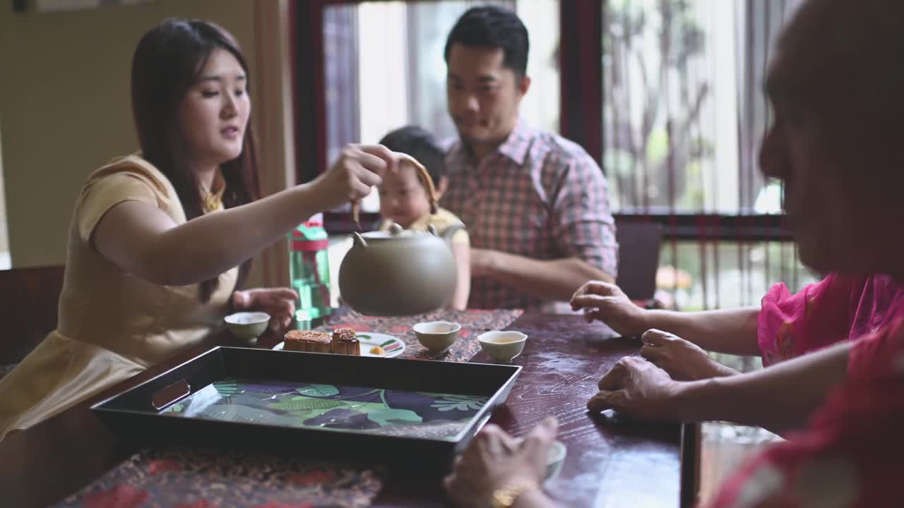 中国女儿在多代同堂期间喝茶，享用传统的节月饼和下午茶聚会期间在家喝茶