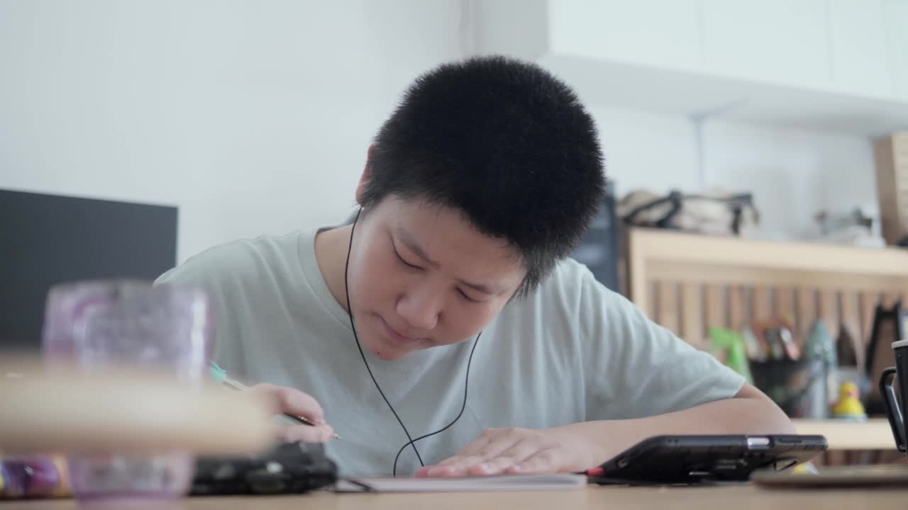 亚洲男孩在COVID-19期间通过智能手机学习在线课程，隔离的生活方式概念。