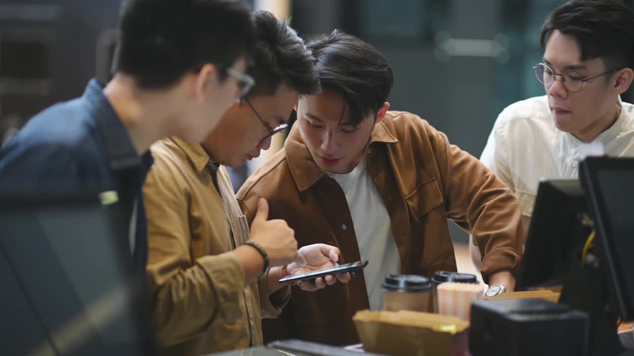 亚洲华人年轻人在电影院前用智能手机在线预订电影票